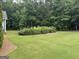 A large grassy backyard featuring a well-manicured lawn and mature shrubs and trees at 180 Cooper Rd, Social Circle, GA 30025