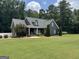 Inviting two-story home with a rocking chair front porch and large, well-maintained front lawn at 180 Cooper Rd, Social Circle, GA 30025