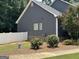 Side view of a home with dark siding, white trim, and a fenced yard with landscaping at 180 Cooper Rd, Social Circle, GA 30025