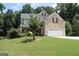 Well-maintained two-story brick home with a two-car garage and lush lawn featuring mature trees at 305 Matthew Cir, Stockbridge, GA 30252