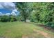 Large backyard with mature trees, a gentle slope, and a small shed, offering ample space for outdoor activities at 1615 Clairmont Sw Ln, Conyers, GA 30094