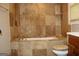 Bathroom features an enclosed stone tiled bath with a beige toilet and wooden vanity at 1627 Orlando Sw St, Atlanta, GA 30311