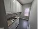 Functional laundry room with ample cabinet space, a utility sink, and a window for natural light at 7910 Tintern Trce, Duluth, GA 30097