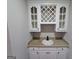A quaint wet bar with a sink, lower cabinets, and glass faced upper cabinets at 7910 Tintern Trce, Duluth, GA 30097