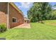 Spacious, grassy backyard with brick patio, mature trees, landscaping, and partial view of brick home at 708 Delanie Way, Stone Mountain, GA 30083
