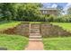 Backyard featuring stone stairs and retaining wall leading to a grassy area with mature trees and a partial view of the home at 708 Delanie Way, Stone Mountain, GA 30083