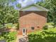 Back exterior of all-brick home showing basement entrance, window, mature trees, and established yard at 708 Delanie Way, Stone Mountain, GA 30083