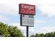 A sign for a Tanger Outlet mall features popular retail brands against a partly cloudy sky at 714 Ocmulgee Crossing, Locust Grove, GA 30248