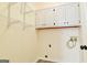 Bright laundry room with wire rack shelving, white cabinets, and utility connections at 165 Mcelwaney Way, Fayetteville, GA 30215