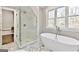 Bright bathroom featuring a glass-enclosed shower, a freestanding tub, and marble tile floors, with a view outside at 4203 Harrogate Nw Dr, Atlanta, GA 30327