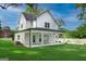 Backyard of a white farmhouse with an expansive lawn, covered patio, and lush greenery at 61 Main St, Moreland, GA 30259
