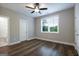 Well-lit bedroom with ceiling fan, neutral walls, and hardwood flooring, door to bathroom is visible at 61 Main St, Moreland, GA 30259
