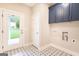 Well-lit laundry room with upper cabinets and attractive patterned tile flooring and backyard views at 61 Main St, Moreland, GA 30259