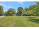 View of sprawling green front lawn with mature trees on a sunny day at 871 Clearwater Rd, Sharpsburg, GA 30277
