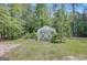 Useful storage shed with crossbuck doors, surrounded by mature trees and a grassy yard at 871 Clearwater Rd, Sharpsburg, GA 30277
