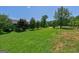 Spacious backyard with green grass, mature trees, and a glimpse of the home's exterior on a sunny day at 1828 Pitts Chapel Rd, Newborn, GA 30056