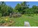 Lush green backyard featuring garden boxes, a partially covered enclosure, and mature trees against a blue sky at 1828 Pitts Chapel Rd, Newborn, GA 30056