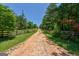 Dirt driveway leading to property, framed by wooden fences and lush greenery at 1828 Pitts Chapel Rd, Newborn, GA 30056