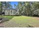 Rear exterior view of home, featuring large yard and mature tree border at 1202 Loxley Cir, Peachtree City, GA 30269