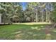View of a large, grassy backyard with mature trees, providing privacy and space for outdoor enjoyment at 1202 Loxley Cir, Peachtree City, GA 30269