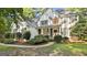 Elegant two-story home featuring a stucco facade, black shutters, and manicured landscaping at 1202 Loxley Cir, Peachtree City, GA 30269
