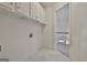 White-painted laundry room with tiled flooring and white storage cabinets at 1202 Loxley Cir, Peachtree City, GA 30269