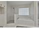 Bright bathroom with separate shower and tub featuring white tile and a window with a blind at 1202 Loxley Cir, Peachtree City, GA 30269