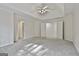 Spacious carpeted main bedroom with tray ceilings, ceiling fan, and double doors to the main bathroom at 1202 Loxley Cir, Peachtree City, GA 30269