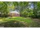 Spacious, green backyard with mature trees and a partial view of a brick home with red shutters at 3260 Russell St, Hapeville, GA 30354