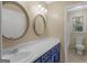 Stylish bathroom featuring double mirrors over a blue vanity and view of a tub/shower combo at 100 Homestead Pl, Rex, GA 30273