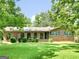 Charming brick home with arched entryways, green lawn and mature trees at 100 Homestead Pl, Rex, GA 30273