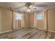 Cozy bedroom featuring wood-look floors, two windows with curtains, and a ceiling fan with lights at 315 Charlotte Blvd, Stockbridge, GA 30281