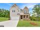 Inviting two-story home boasts a 2-car garage, a blend of gray siding, brick accents, and a covered front porch at 7530 W Homer Dr, Cumming, GA 30028