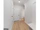 Bright hallway with light hardwood floors, white walls, white trim, and access to various rooms at 7530 W Homer Dr, Cumming, GA 30028