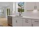Modern kitchen features a stainless steel dishwasher, a sink under a window, and white cabinets at 7530 W Homer Dr, Cumming, GA 30028