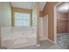 Bathroom with large white tub, shower, and window view, plus tile floor at 204 Eleanor Court, Stockbridge, GA 30281