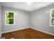 A bedroom features hardwood floors, gray walls, white trim, and two windows providing natural light at 1783 Cheyenne Trl, Jonesboro, GA 30236