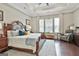 Inviting primary bedroom features a tray ceiling, hardwood floors, and a large window for ample natural light at 135 Adam Ridge Ln, Fayetteville, GA 30214