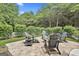 Inviting outdoor patio with brick pavers, a fire pit, and Adirondack chairs, surrounded by lush landscaping at 135 Adam Ridge Ln, Fayetteville, GA 30214