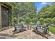 Inviting outdoor patio with brick pavers, a fire pit, and Adirondack chairs, surrounded by lush landscaping at 135 Adam Ridge Ln, Fayetteville, GA 30214