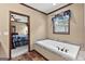 Bathroom showcasing a soaking tub with wood-look tile, and a view into the main bedroom at 80 David Rd, Hampton, GA 30228