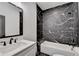 Modern bathroom featuring black and white marble-look tile surrounding a tub with shower at 2255 Buford Dam Rd, Buford, GA 30518