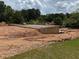 Newly installed basement foundation with dirt backfill, with lawn and surrounding trees at 2257 Buford Dam Rd, Buford, GA 30518