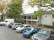 View of a parking lot showing multiple cars parked outside of the condos with mature trees and landscaping at 1150 Collier Nw Rd # H6, Atlanta, GA 30318