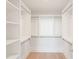 Bright walk-in closet with custom shelving, hanging rods, and hardwood floors at 10871 Serenbe Ln, Chattahoochee Hills, GA 30268