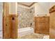 Bathroom showing a tub with tiled walls and a wood accent wall with paneling at 6219 Woodlake Dr, Buford, GA 30518