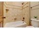Bathroom featuring white tiled walls, a built-in corner shelf, and a white bathtub with shower fixtures at 6219 Woodlake Dr, Buford, GA 30518