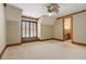 Bedroom with carpet, wood trim, shutters, bathroom view and decorative ceiling fan at 6219 Woodlake Dr, Buford, GA 30518