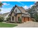 Exterior view of the home featuring stone and brick exterior, well maintained lawn, and wood garage doors at 6219 Woodlake Dr, Buford, GA 30518