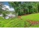 Scenic lake view from a lush, green lawn with mature trees and a private dock, offering serene waterfront living at 6219 Woodlake Dr, Buford, GA 30518